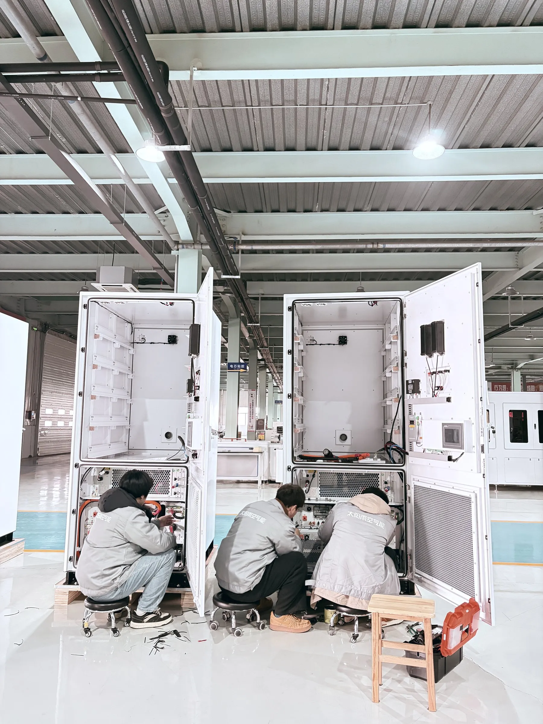 Tres técnicos cableando cabinets de baterías en la línea de integración